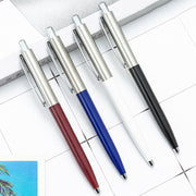 Bốn bút bi với thân màu đỏ, xanh, trắng, đen, nắp kim loại, nằm trên nền giấy trắng.