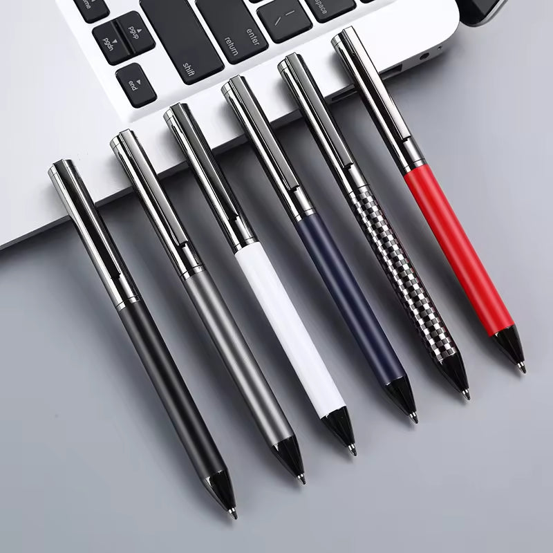 Sáu cây bút bi nhiều màu sắc, đặt cạnh bàn phím laptop màu bạc trên nền xám.