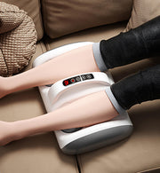 Máy massage chân màu trắng, hiển thị đèn LED đỏ, đặt trên ghế sofa nâu.