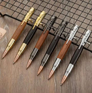 Sáu bút bi màu vàng, đen, bạc, và gỗ xếp trên lưới đen, nền gỗ nâu nhạt.