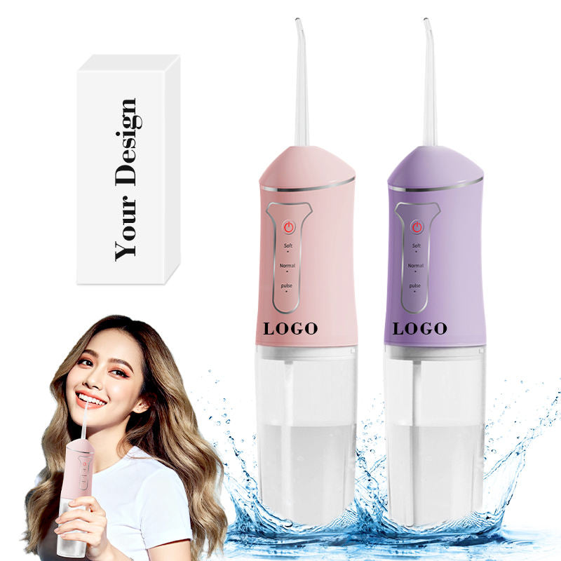 Hai máy tăm nước màu hồng và tím, nền trắng, có nước bắn và người cầm tăm nước.