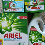 Các hộp và chai bột giặt Ariel, màu xanh lá và trắng, với logo xoáy nổi bật.