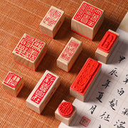 Các con dấu gỗ với hoa văn đỏ và chữ Hán trên nền vải màu cam.