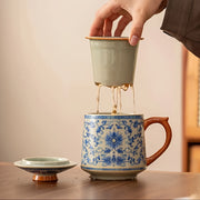 Người rót trà vào cốc có hoa văn xanh, nắp và đĩa lót màu xanh nhạt, nền màu be.