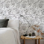 Giường trắng, gối xám, bàn nhỏ với đèn đen, nền tường hoa lớn trắng đen.