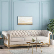Sofa màu kem, tường xanh, tranh trừu tượng, bàn tròn gỗ, cây xanh bên phải.