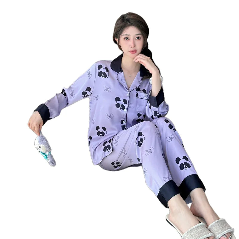 Người mặc bộ đồ ngủ màu tím nhạt có họa tiết gấu trúc, viền đen, cầm thú bông nhỏ.