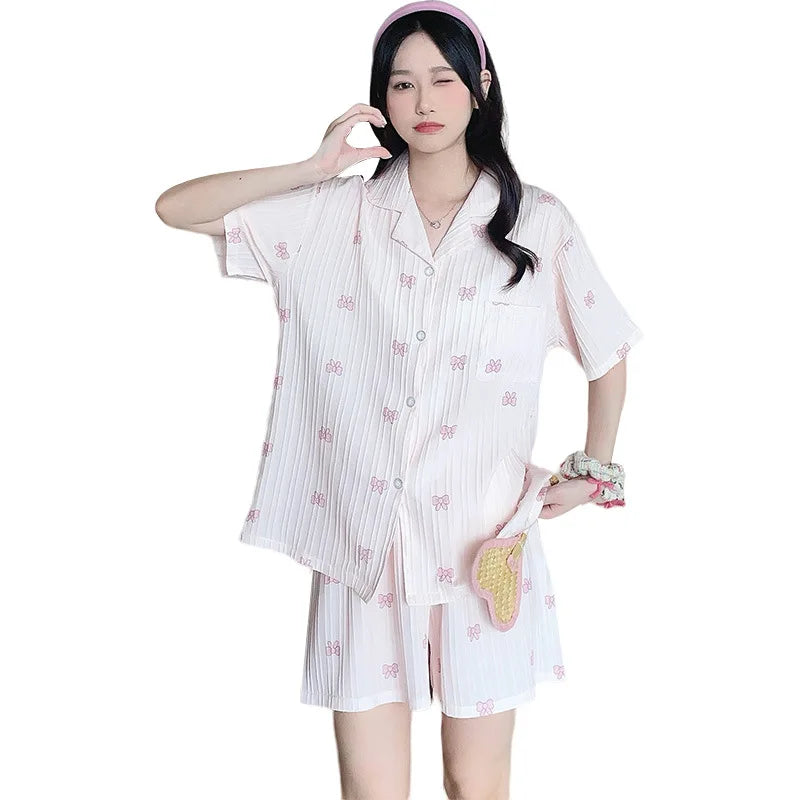 Người phụ nữ mặc đồ ngủ trắng họa tiết nơ hồng, đội băng đô hồng, đứng tạo dáng.