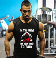 Người đàn ông mặc áo đen với chữ trắng, tập gym, nền xanh da trời và thiết bị thể dục.