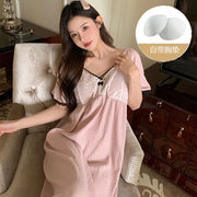 Cô gái mặc váy hồng nhạt ren trắng ngồi ghế, tóc dài, kẹp tóc hồng. Viên lót ngực bên phải.