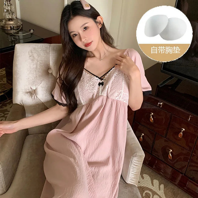 Cô gái mặc váy hồng nhạt ren trắng ngồi ghế, tóc dài, kẹp tóc hồng. Viên lót ngực bên phải.