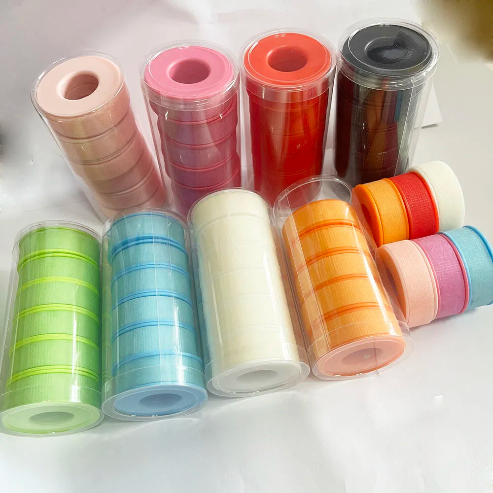 Các cuộn băng dính màu sắc khác nhau trong hộp nhựa: xanh lá, xanh dương, trắng, cam, đỏ, hồng, đen.