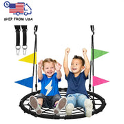 Hai đứa trẻ ngồi trên xích đu tròn đen với cờ màu xanh, vàng, hồng, vui vẻ giơ tay lên.