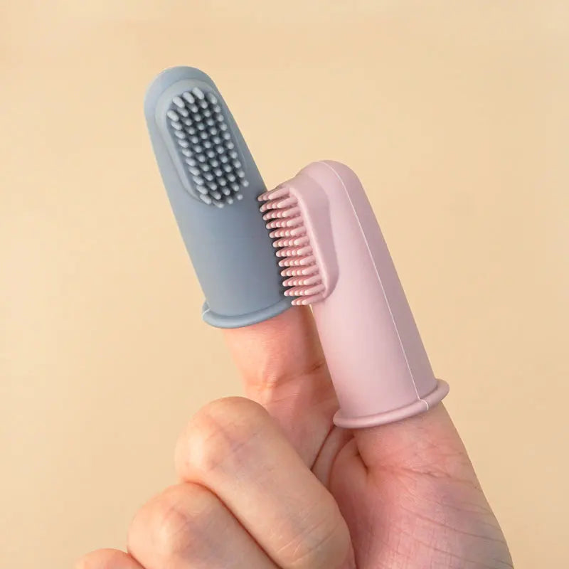 Hai bàn chải silicon, một màu xanh xám, một màu hồng, đặt trên ngón tay.