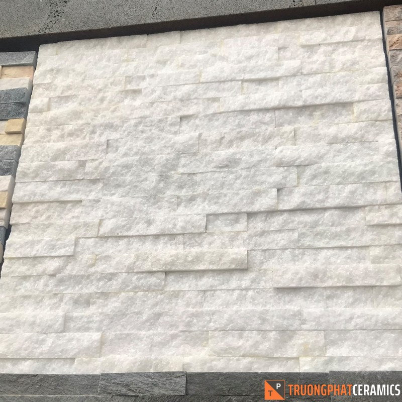 Tường gạch màu trắng xếp lớp, nền xám đậm ở trên và viền đen ở hai bên.