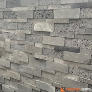 Tường gạch xếp chồng màu xám, họa tiết lỗ nhỏ, bề mặt thô và tự nhiên.