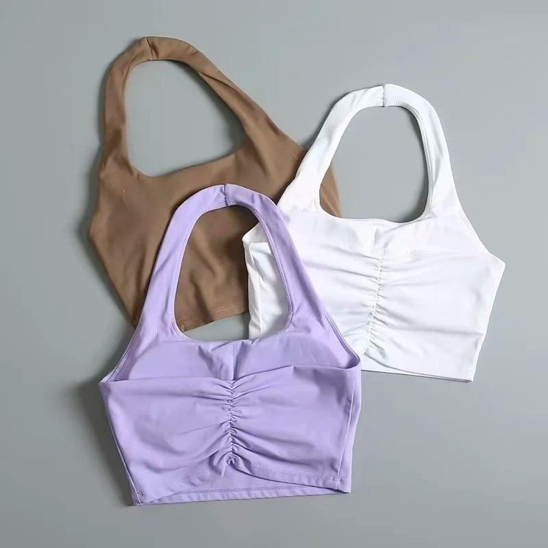 Ba áo crop top màu nâu, trắng và tím nhạt trên nền xám, có chi tiết nhún ở giữa.