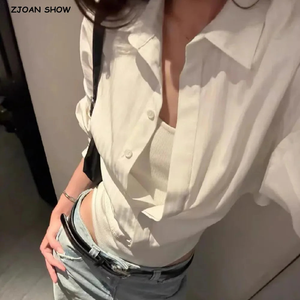 Người mặc áo sơ mi trắng, áo hai dây bên trong, quần jeans xanh, thắt lưng đen.