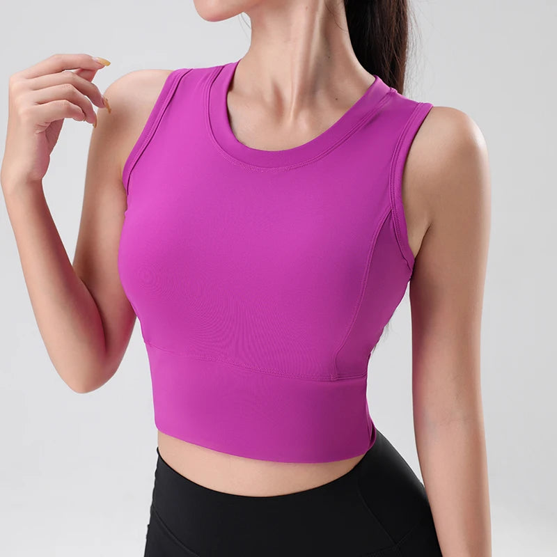Người mặc áo crop top tím, quần đen trên nền xám nhạt.