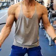 Người đàn ông mặc áo ba lỗ màu xám, quần xanh dương, đang tập luyện trong phòng gym.