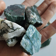Các khối đá xanh rêu và trắng, hoa văn tự nhiên, nằm trên lòng bàn tay người.