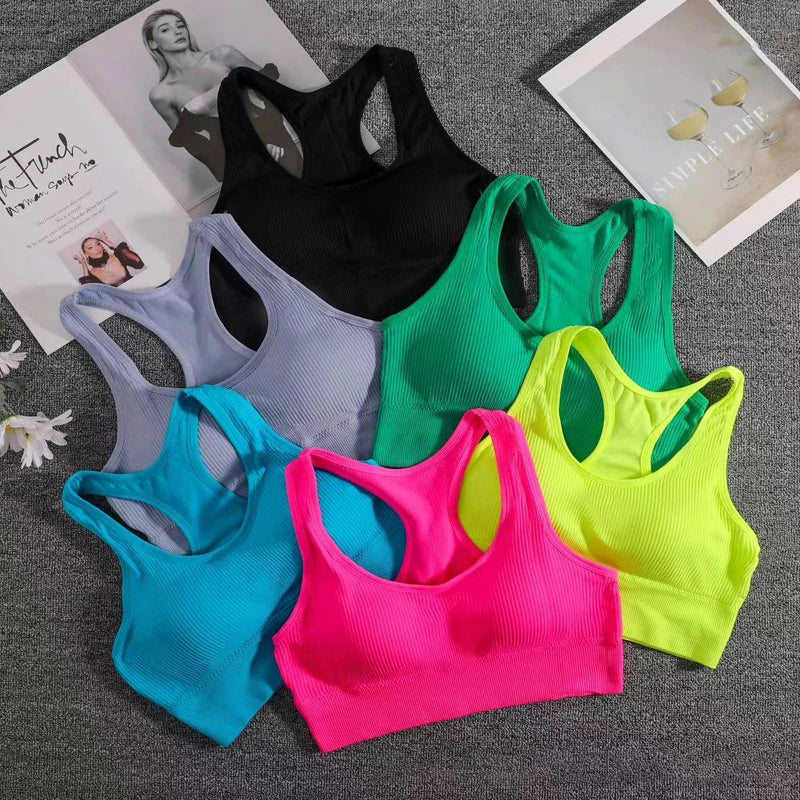 Bảy áo tập nhiều màu: đen, xám, xanh lá, xanh dương, hồng, vàng nhạt trên nền vải xám.