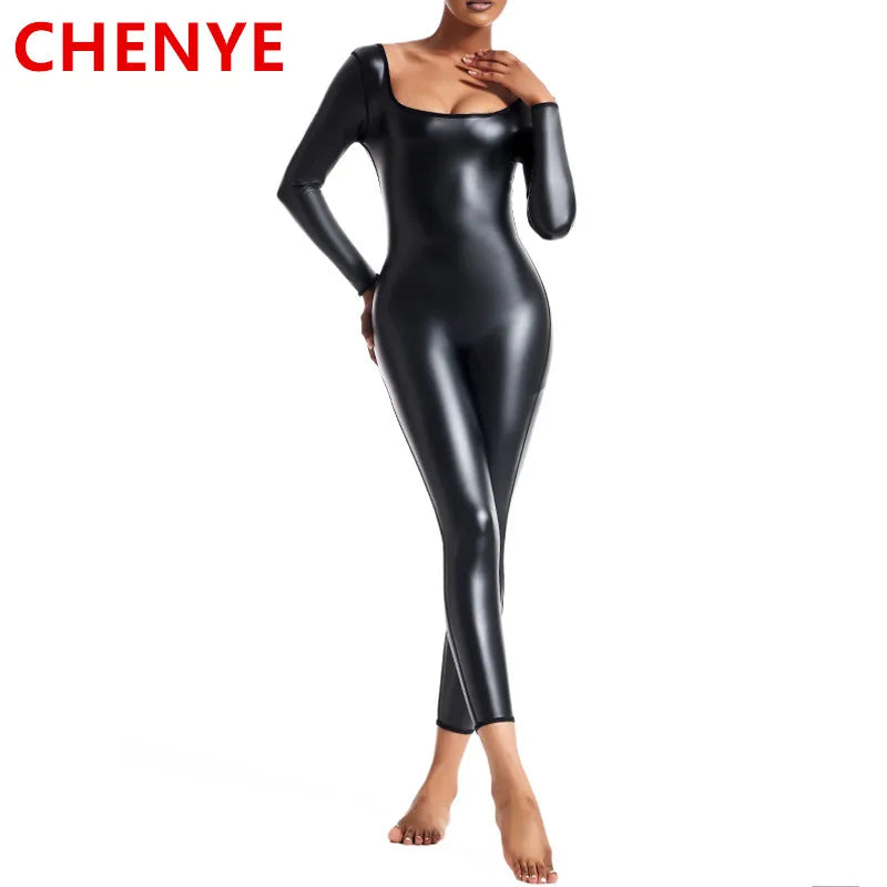 Người mẫu mặc bộ bodysuit đen bóng dài tay, đứng trên nền trắng.