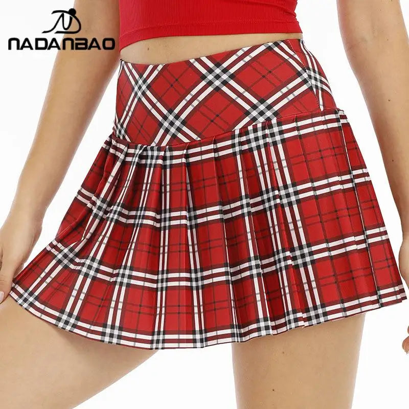 Chân váy xếp ly họa tiết caro đỏ, trắng và đen, áo crop top đỏ.