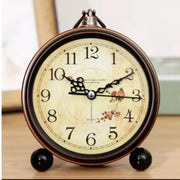 Đồng hồ cổ điển với mặt số hoa văn hoa hồng, kim đen, nền vàng nhạt, số đen rõ ràng.