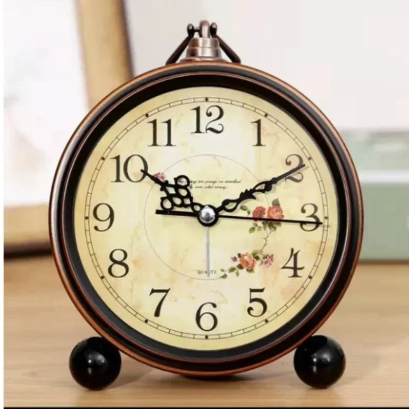 Đồng hồ cổ điển với mặt số hoa văn hoa hồng, kim đen, nền vàng nhạt, số đen rõ ràng.