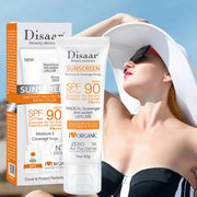 Kem chống nắng Disaar SPF 90, nền trắng chữ cam, phụ nữ đội mũ trắng và kính đen.