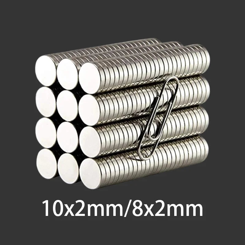 Các nam châm tròn xếp chồng, kẹp giấy kim loại, nền xám, kích thước 10x2mm/8x2mm.