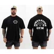 Người mặc áo đen có logo "Powerhouse Gym" trắng, quần ngắn xám, đội mũ lưỡi trai be.