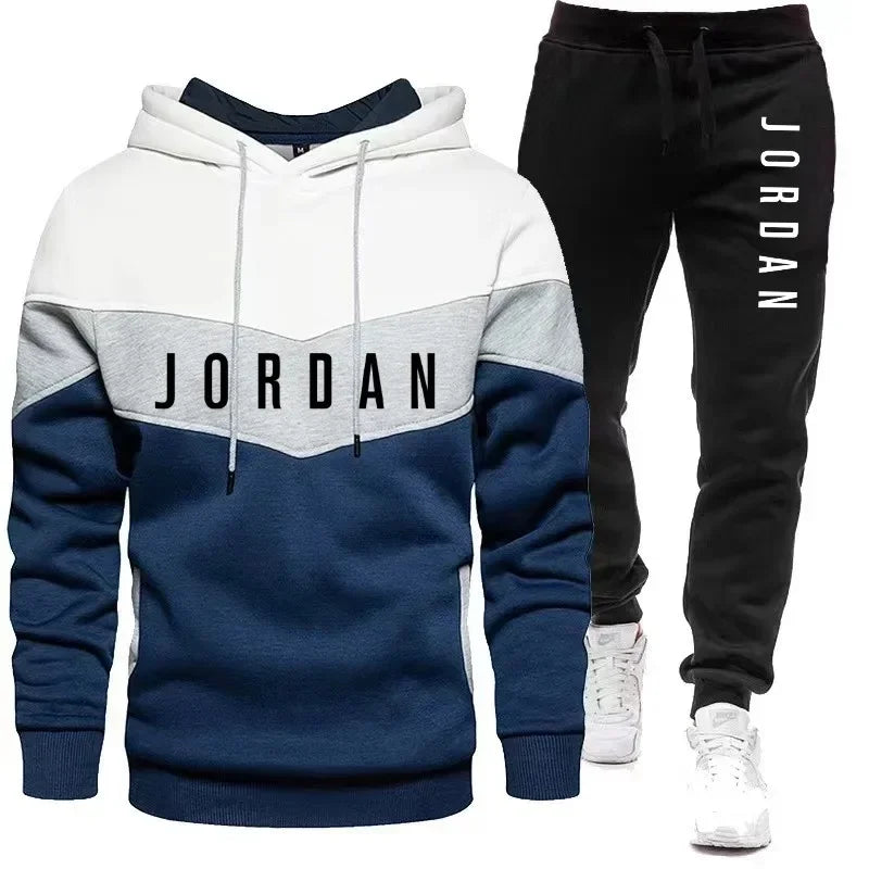 Áo hoodie xanh trắng xám và quần đen, chữ "Jordan" in trên cả hai món, giày thể thao trắng.