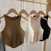 Bốn áo tank top màu nâu, trắng, be, và đen treo trên móc gỗ, trên giá treo đồ.