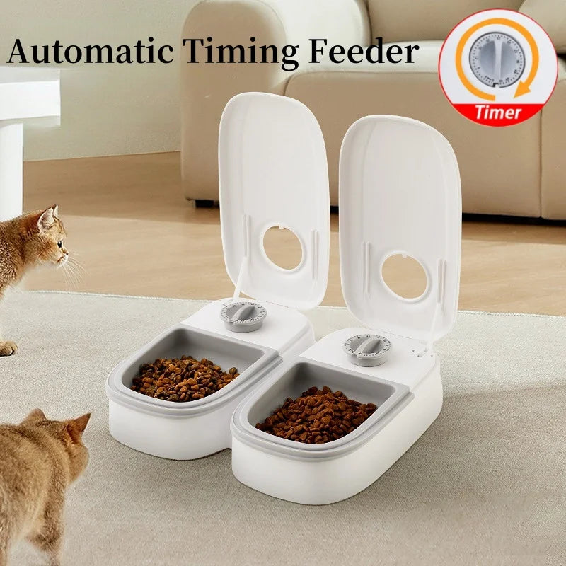 Máy cho ăn tự động trắng, hai ngăn mở nắp, có thức ăn cho mèo trên thảm.