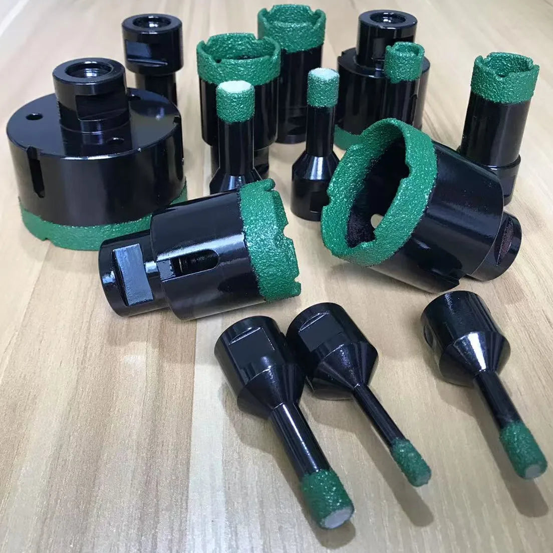 Bộ dụng cụ kim loại đen với đầu màu xanh lá trên bề mặt gỗ sáng.