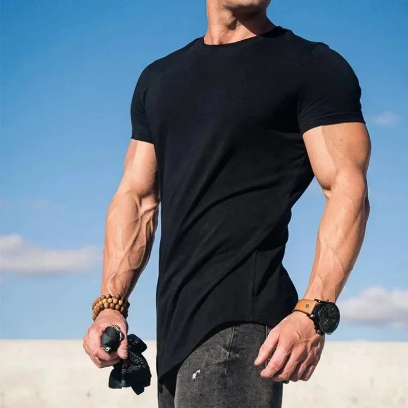 Người mặc áo đen, quần jeans tối màu, đứng dưới bầu trời xanh, tay đeo đồng hồ và vòng tay.