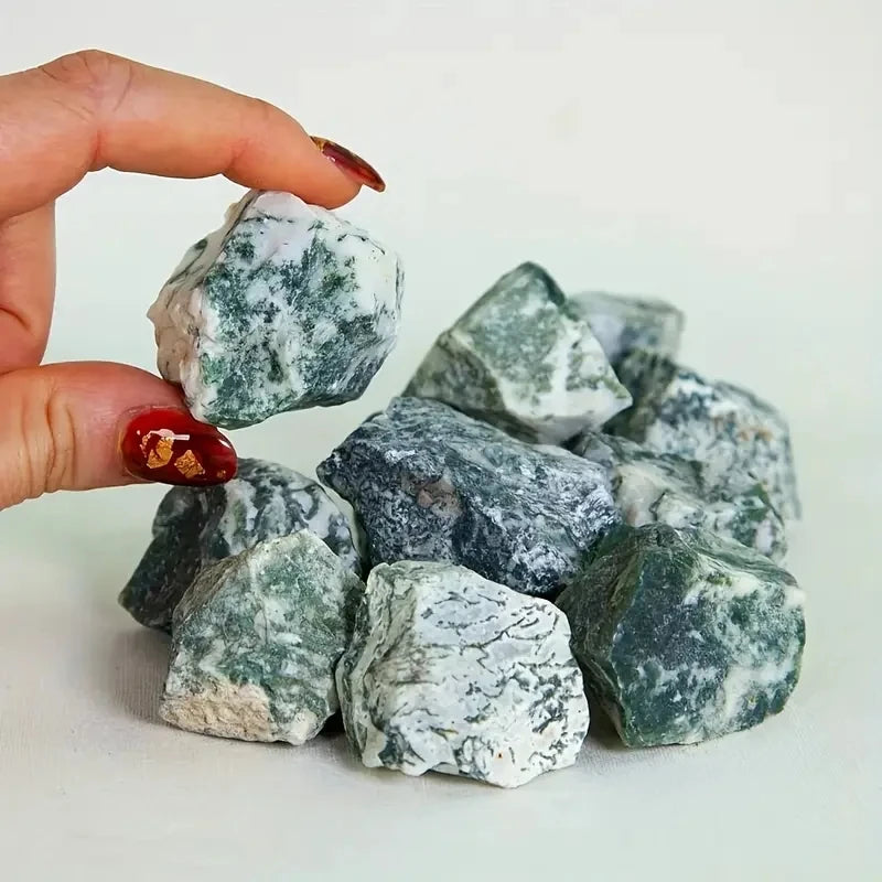 Tay cầm viên đá xanh trắng, xung quanh là nhiều viên đá tương tự, móng tay sơn đỏ.