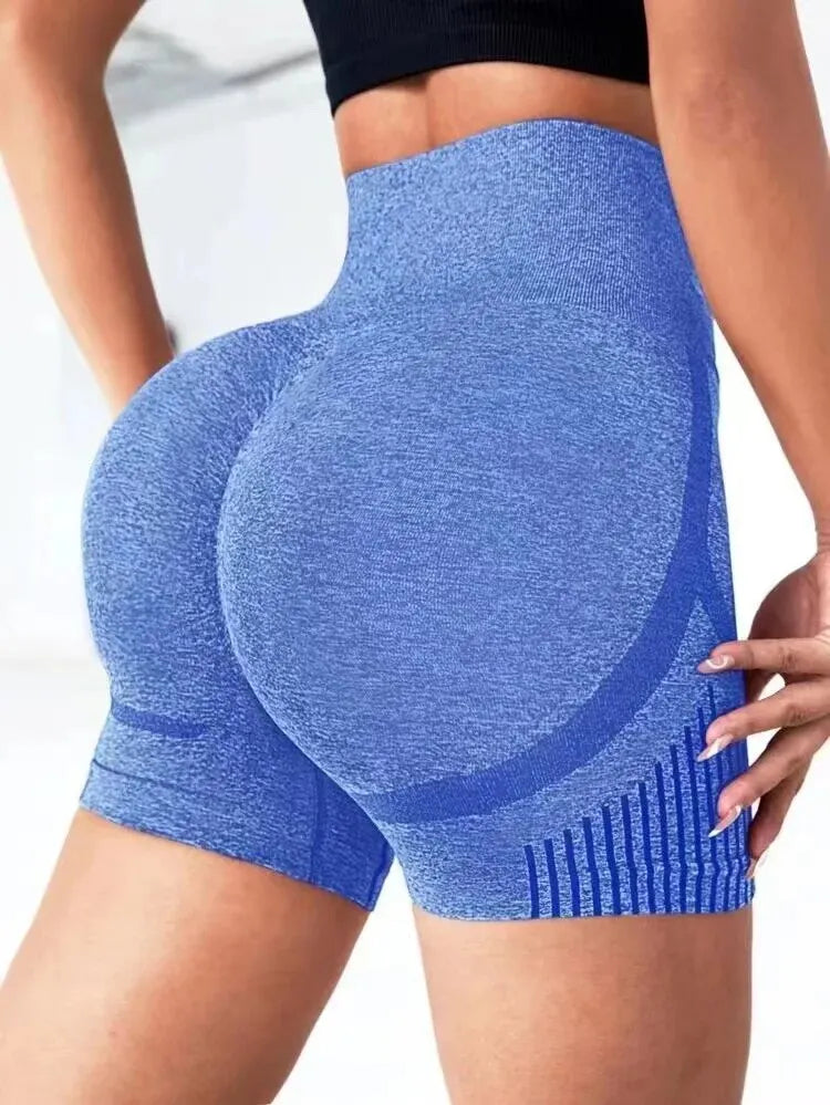 Người mặc quần tập màu xanh dương ôm sát, áo đen, trong không gian sáng.
