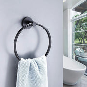 Vòng treo khăn đen trên tường xám, khăn bông xanh nhạt, bồn tắm trắng cạnh cửa sổ lớn.