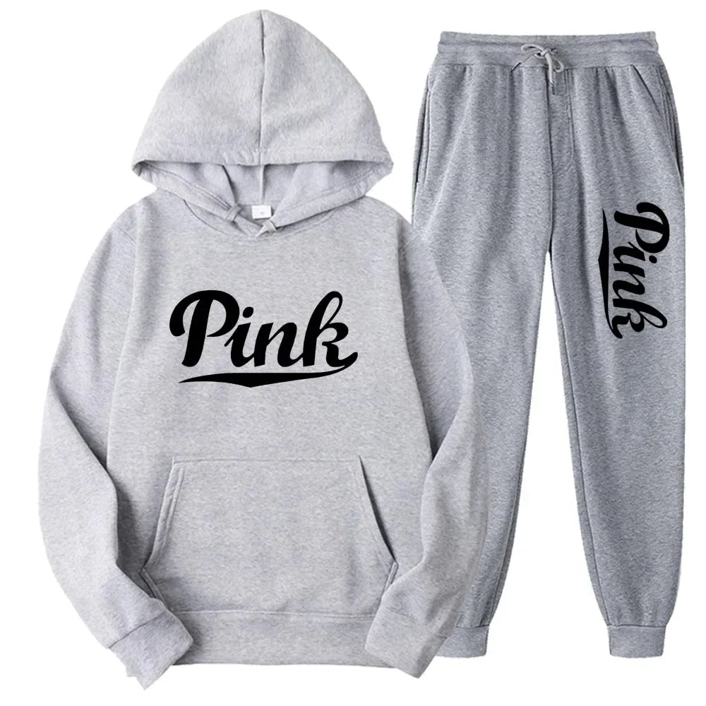 Bộ đồ thể thao xám, áo hoodie và quần dài có chữ "Pink" đen trên ngực và ống quần.