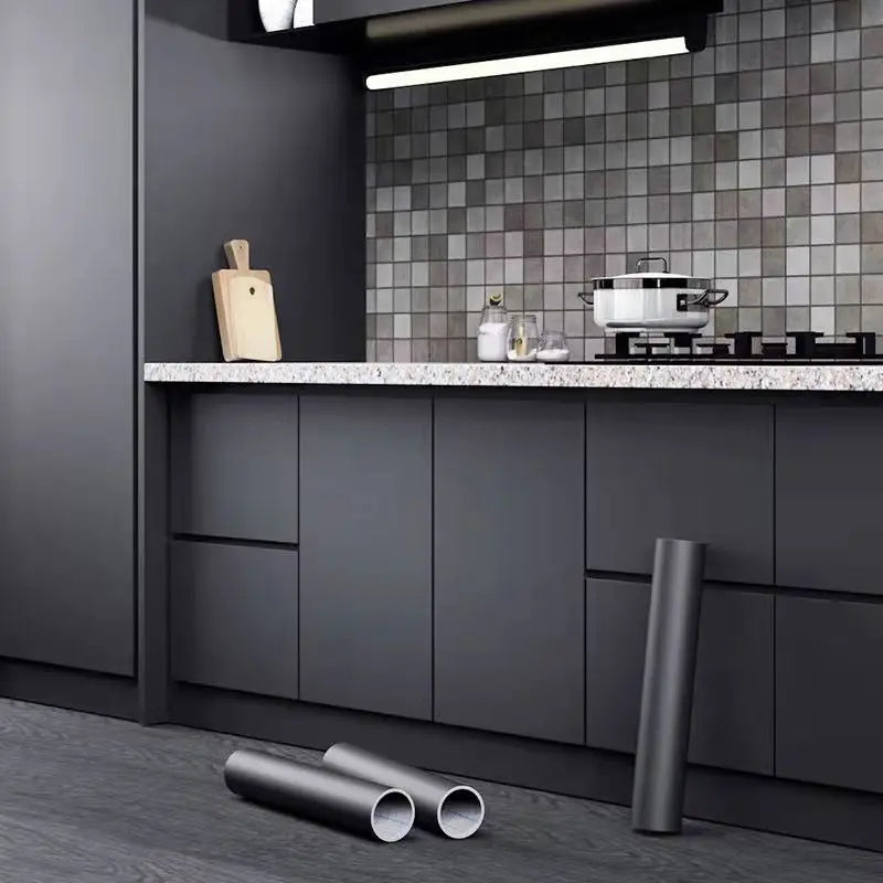 Nhà bếp tông xám, tường lát gạch vuông nhỏ, có nồi trên bếp và ống kim loại dưới sàn.
