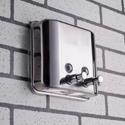 Máy sấy tay kim loại gắn tường trên nền gạch trắng xám.