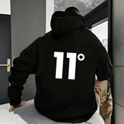 Người mặc áo hoodie đen có số "11°" trắng lớn phía sau, ngồi gần cửa sổ.
