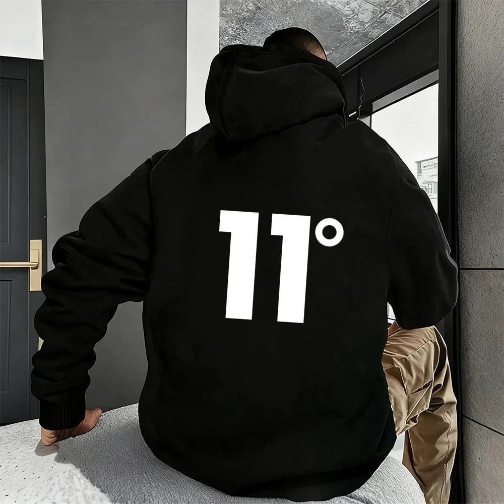 Người đang mặc áo hoodie màu đen in số "11°" trắng lớn ở lưng, ngồi trong phòng.