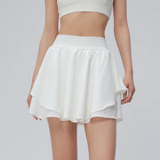 Người mặc áo crop top trắng và váy xòe ngắn màu trắng.