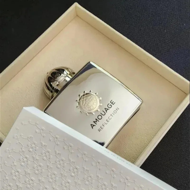 Chai nước hoa màu bạc trong hộp, nền đen, chữ nổi bật trên chai.