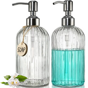 Hai bình xà phòng thủy tinh, một trong suốt, một xanh, có vòi kim loại; hoa trắng bên trái.