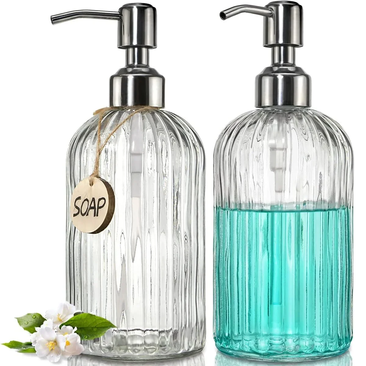 Hai bình xà phòng thủy tinh, một trong suốt, một xanh, có vòi kim loại; hoa trắng bên trái.